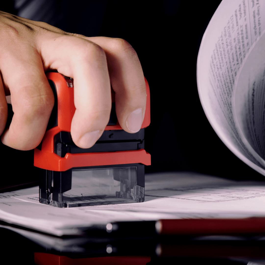 A person is stamping a piece of paper with a red stamp