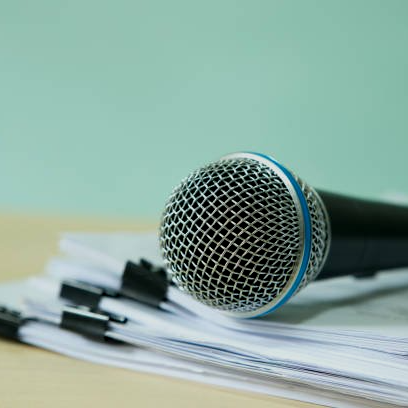 A microphone is sitting on top of a pile of papers.