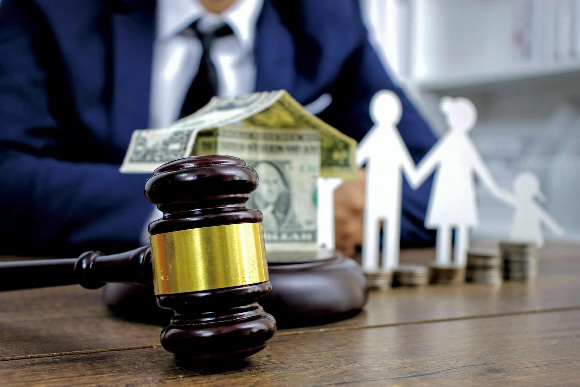 A judge 's gavel is sitting on a wooden table next to a model of a house and a family.