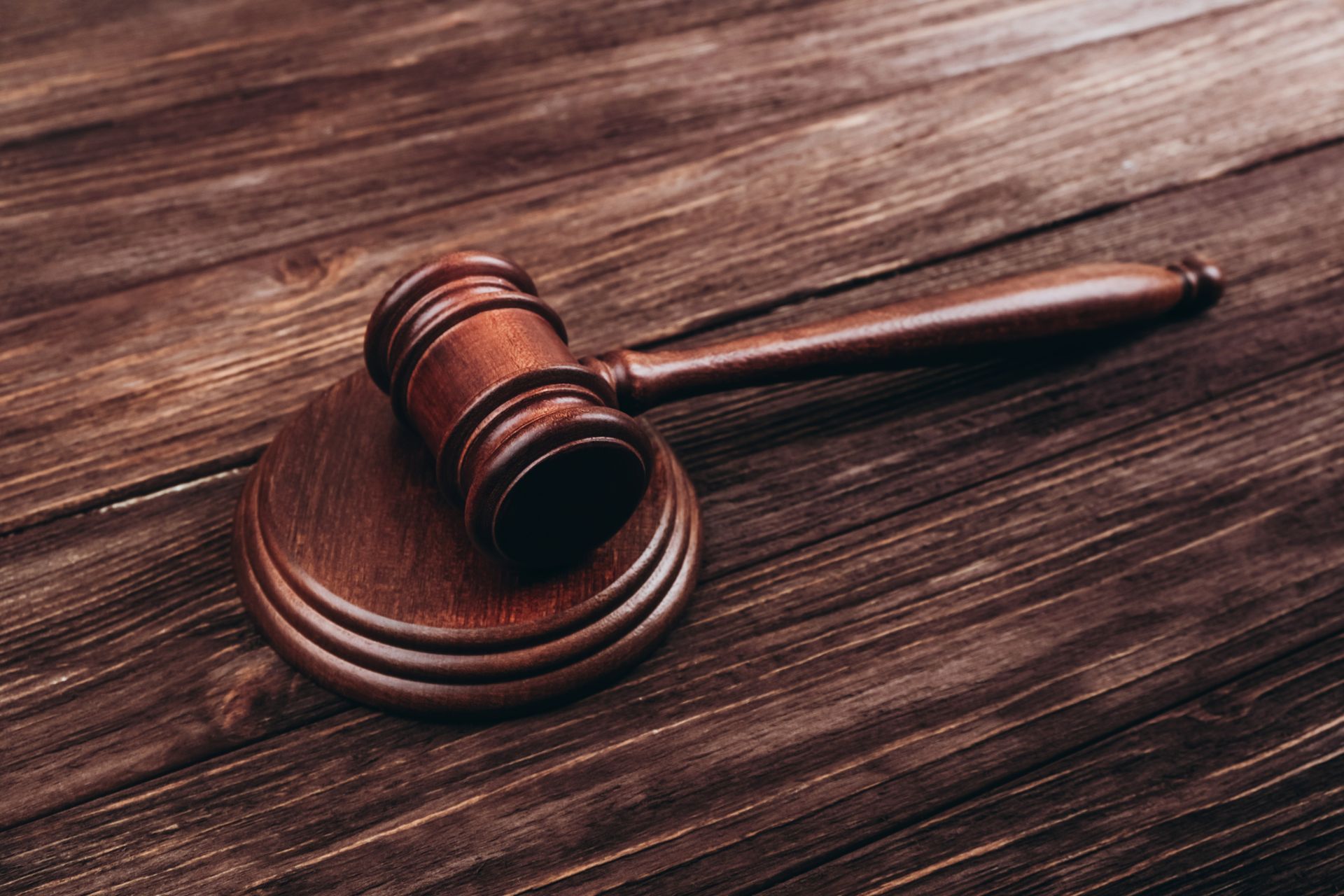 A wooden judge 's gavel is sitting on a wooden table.