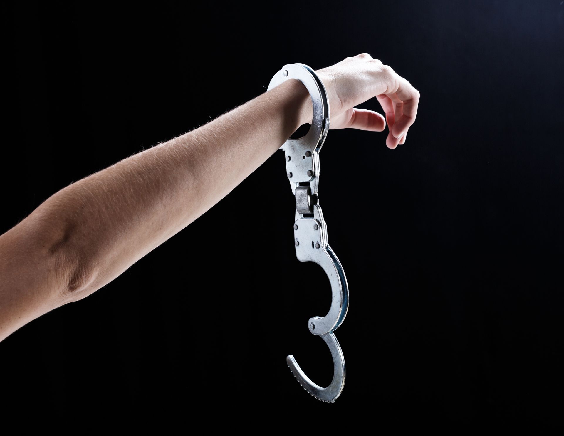 A woman's hand, holding up a wrist with a single, open handcuff, showcasing bail bond services.