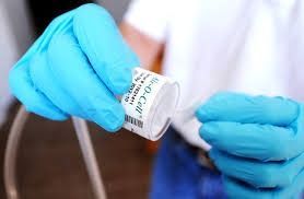 Person in blue gloves holds a small jar of 