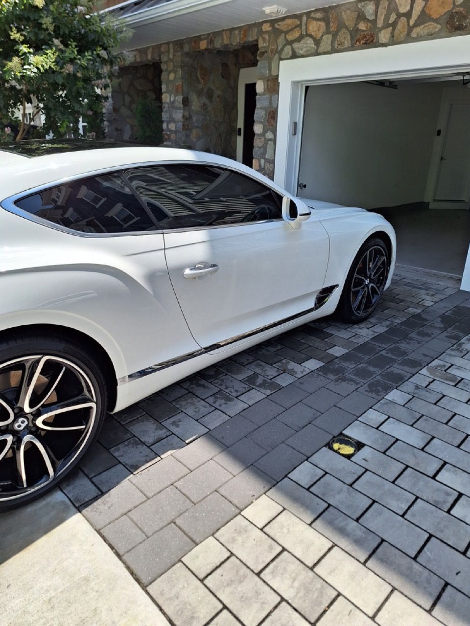 A white bentley continental gt is parked in front of a garage.