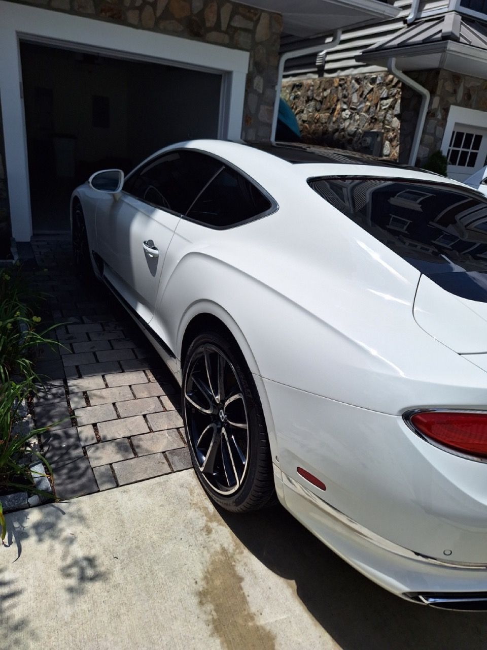 A white sports car is parked in front of a garage