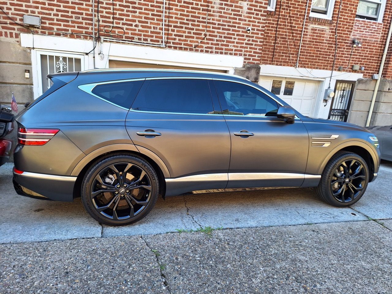 A gray suv is parked in front of a brick building.