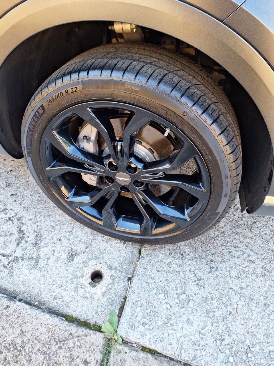 A close up of a car wheel on a sidewalk.