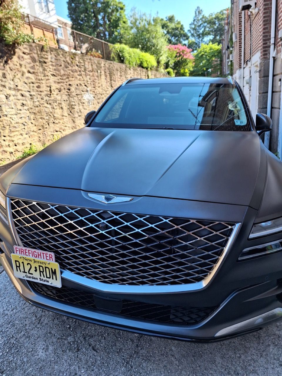 A black car with a new york license plate is parked in front of a building.