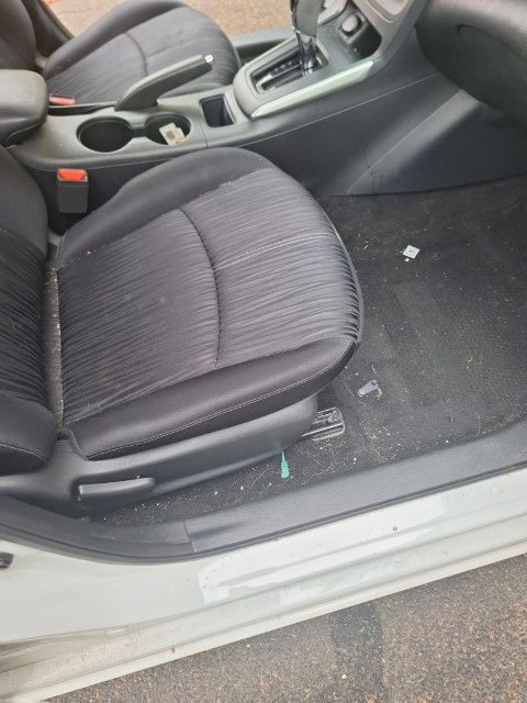 A white car with black seats is parked on the side of the road.