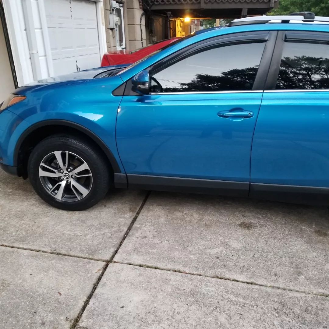 A blue car is parked in front of a garage door