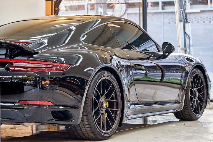 A black sports car is parked in a garage.