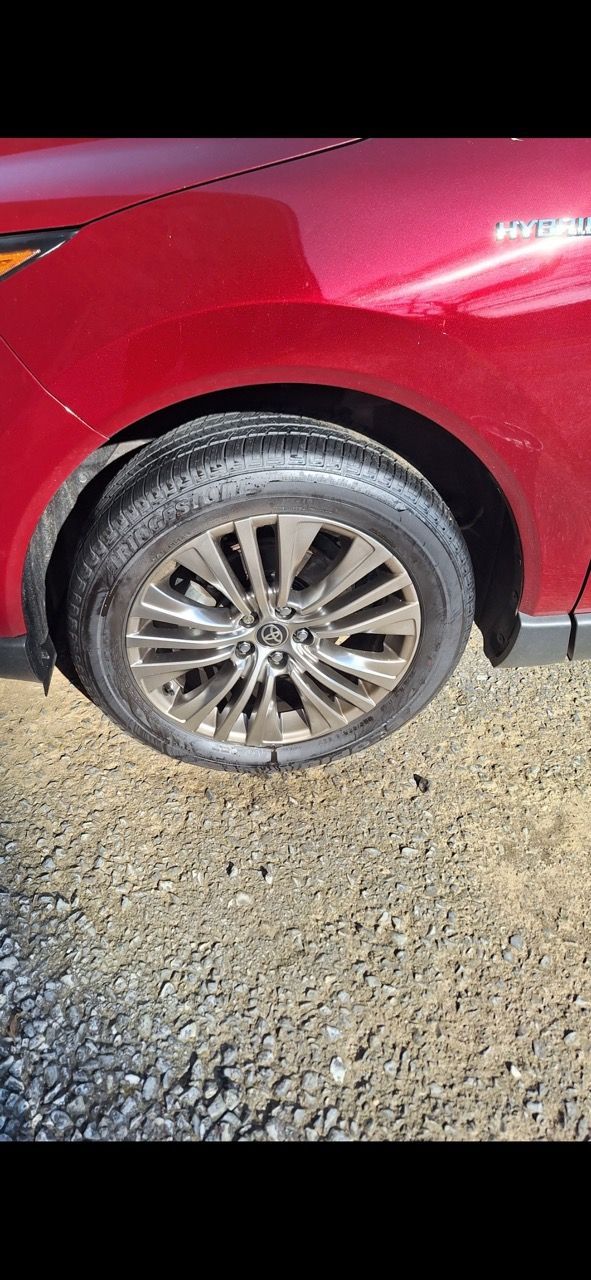 A close up of a red car 's tire on a gravel road.
