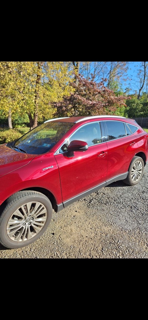 A red car is parked in a gravel lot.