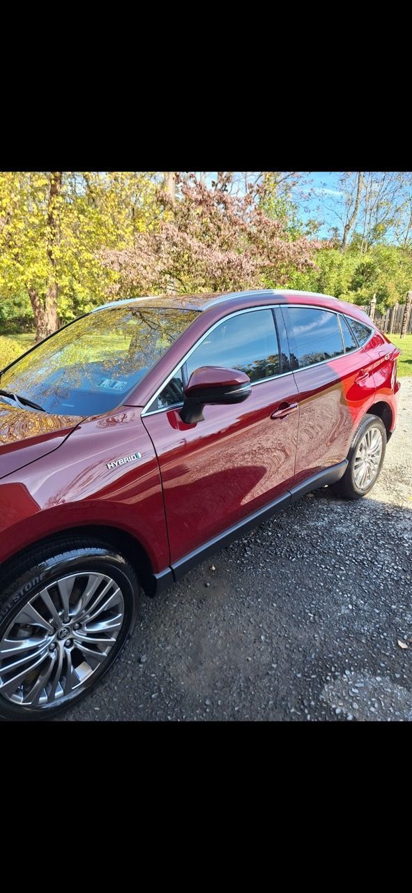 A red car is parked in a gravel lot.