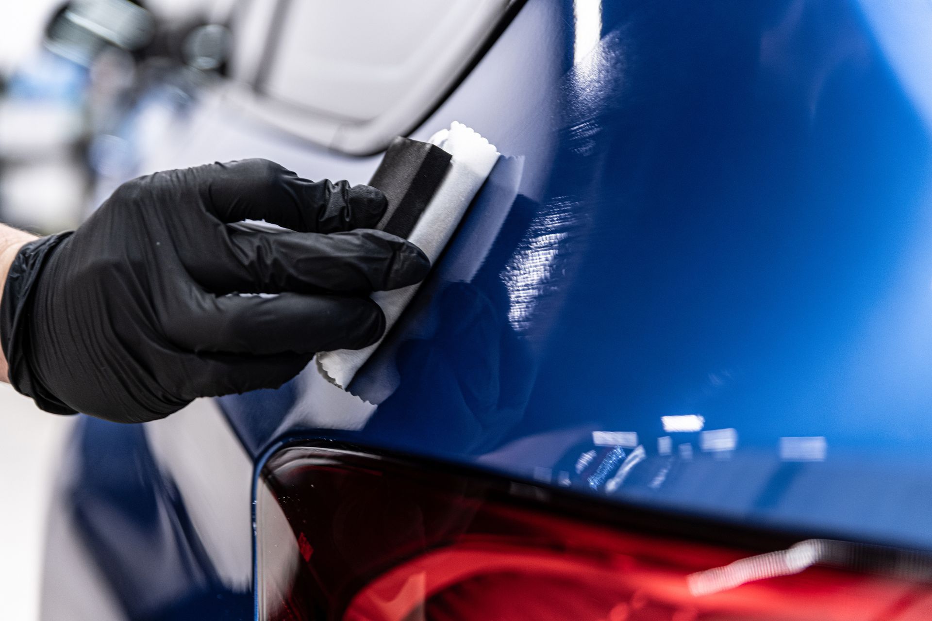Close-up of a blue ceramic coating being applied to a car.