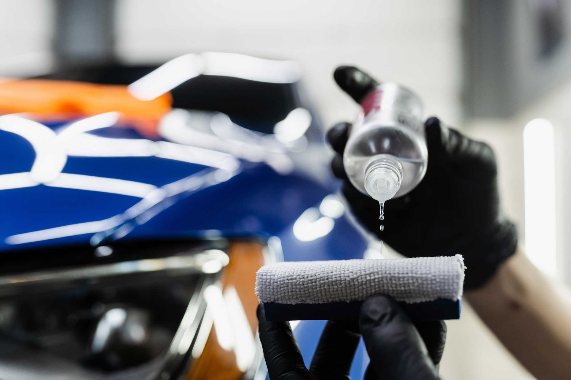 A detailing service worker applies ceramic protective liquid on a sponge close-up.