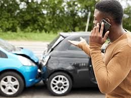 Car accident victim standing near a damaged vehicle while speaking on the phone, possibly calling for help. Car accident victim standing near a damaged vehicle while speaking on the phone, possibly calling for help.