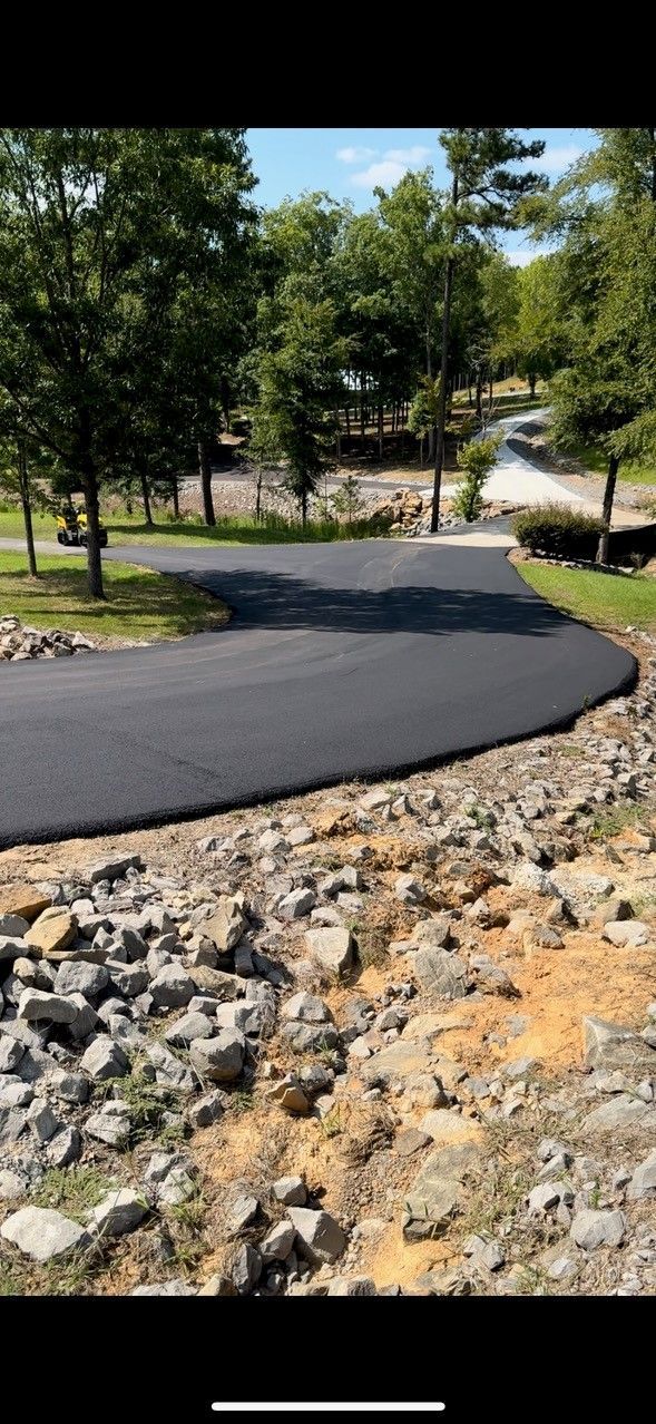 A newly paved road is surrounded by rocks and trees.