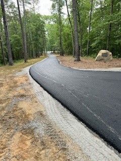 A curvy road going through a forest with trees on both sides.