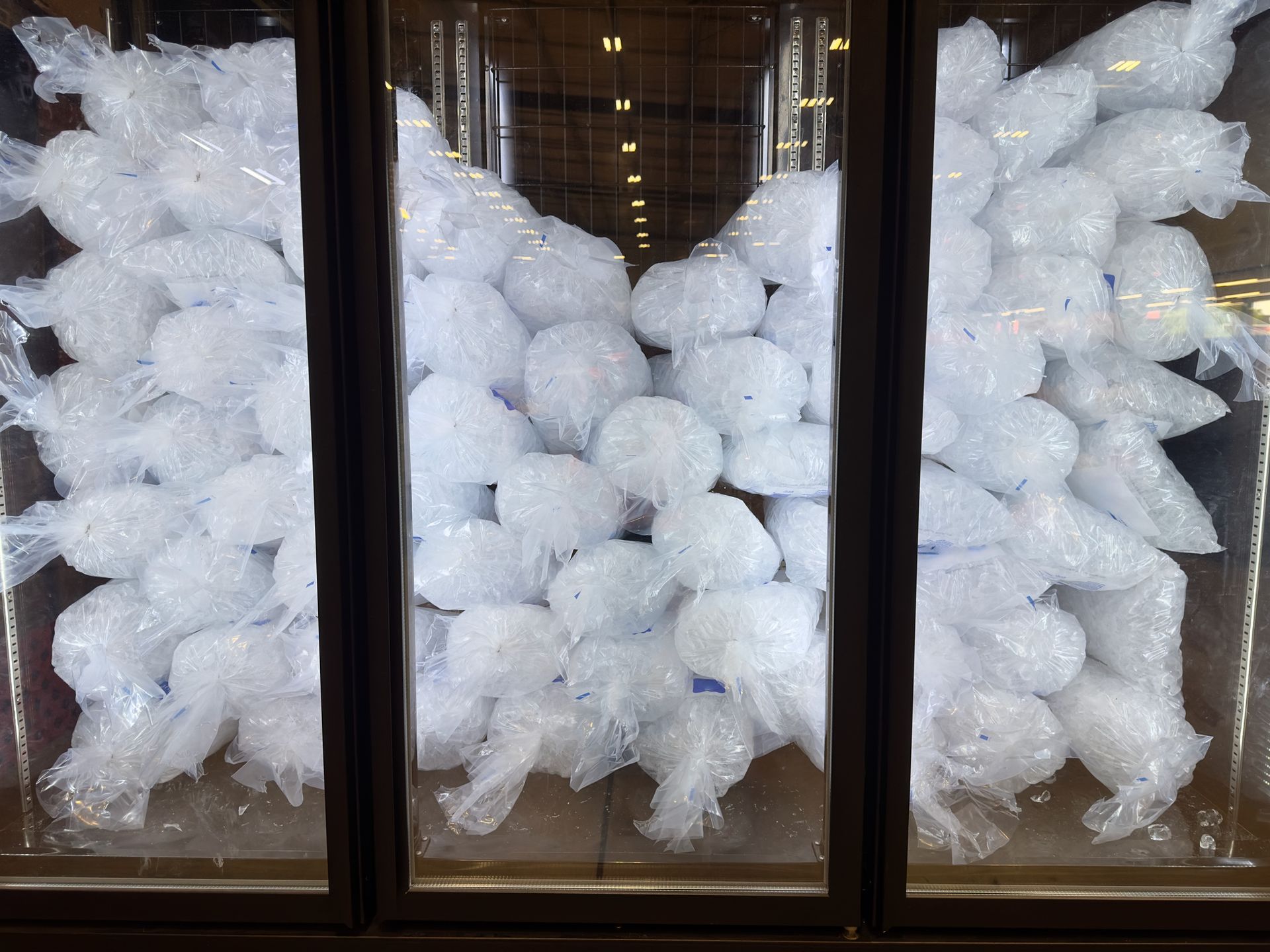 Individual packs of cubed ice selling in a supermarket vertical freezer.