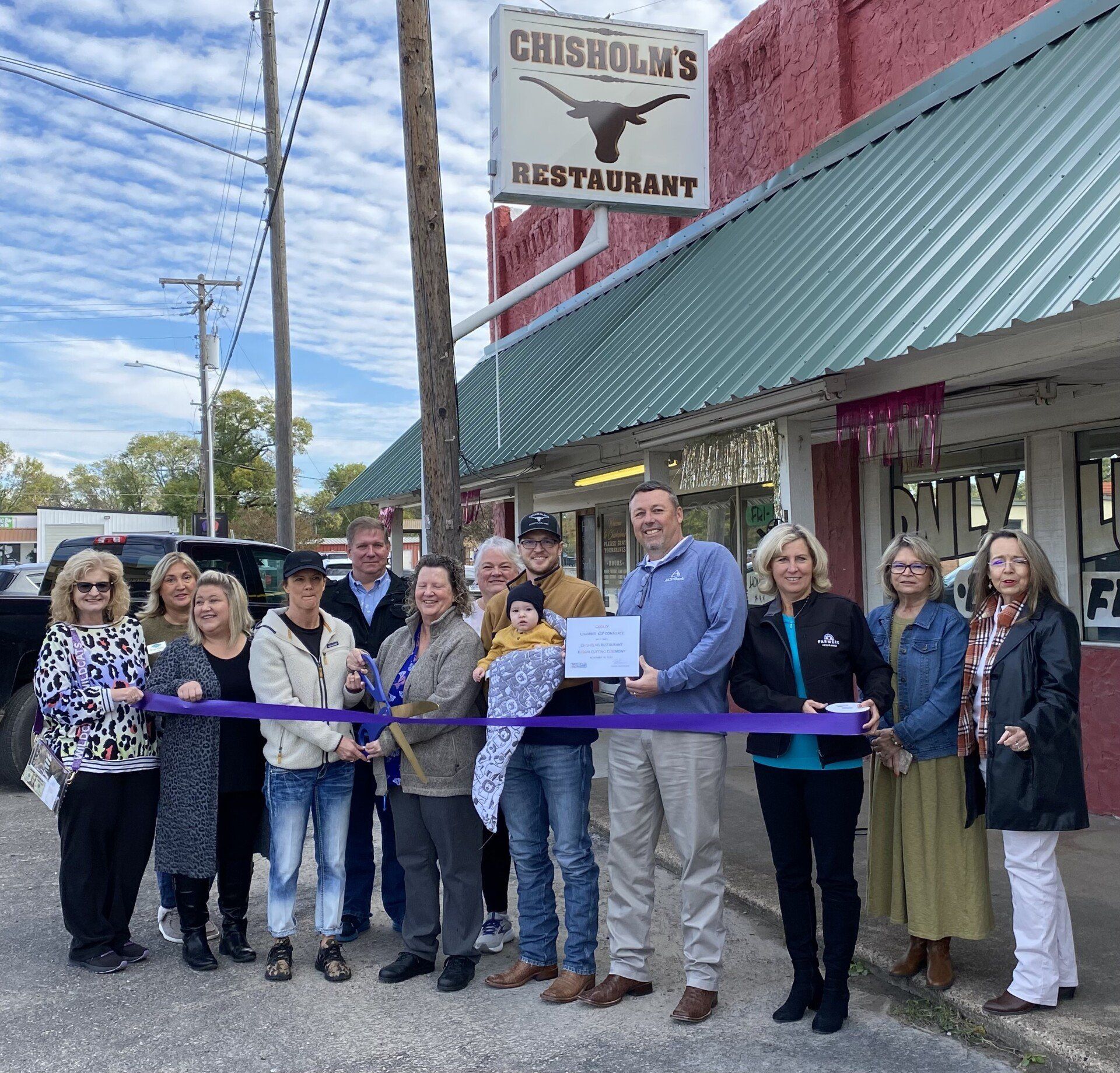 A group of people standing in front of chisholm 's restaurant