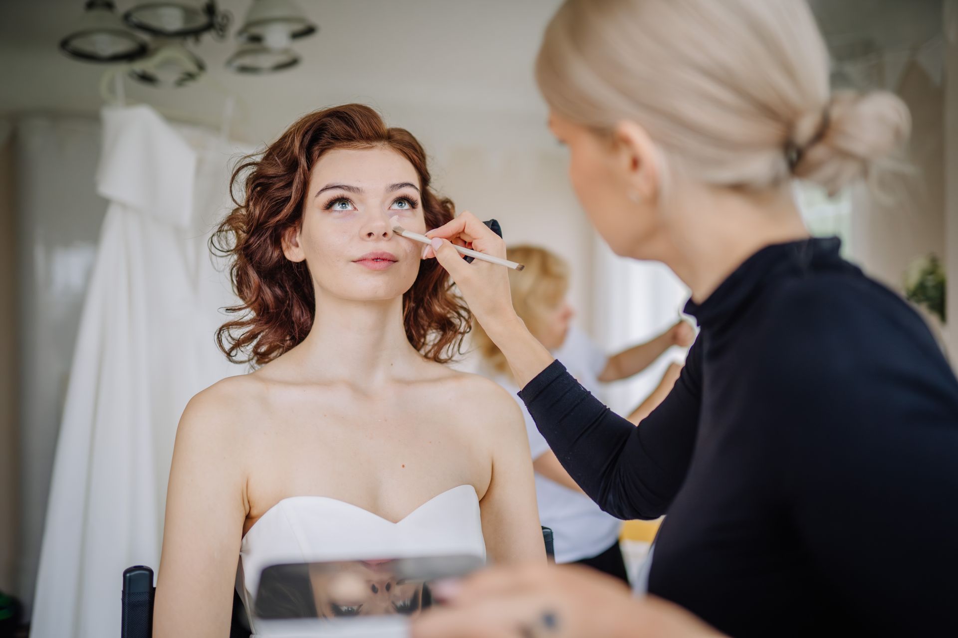 A woman is getting her makeup done by a makeup artist.