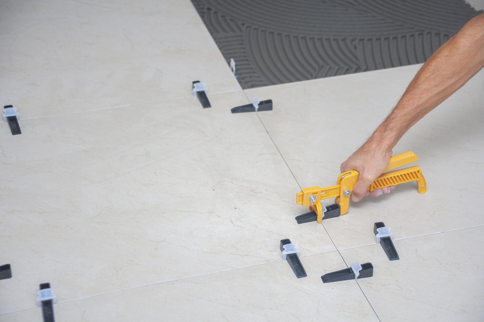 A worker installing tile flooring in a Richland bathroom