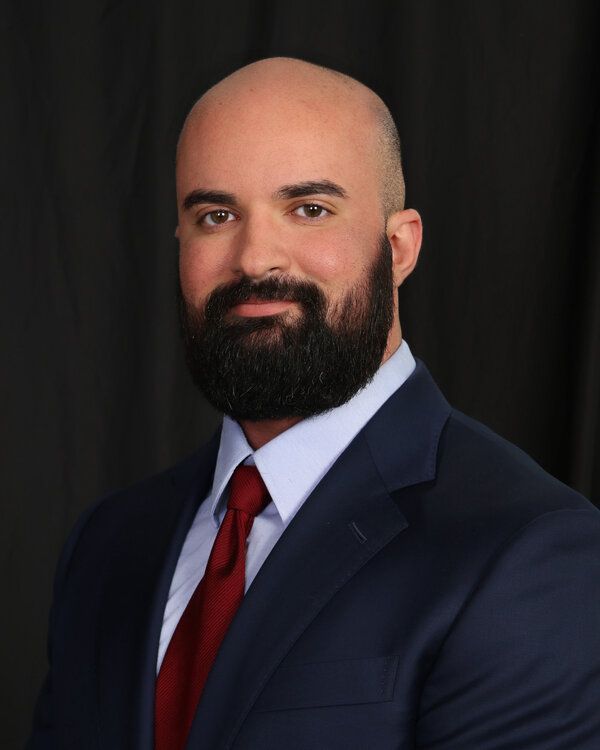 A bald man with a beard is wearing a suit and tie.