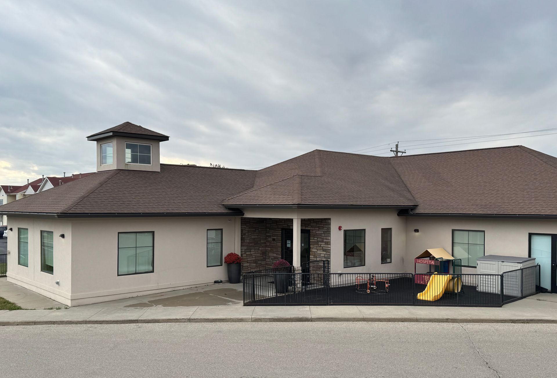Tan building with brown roof and playground.