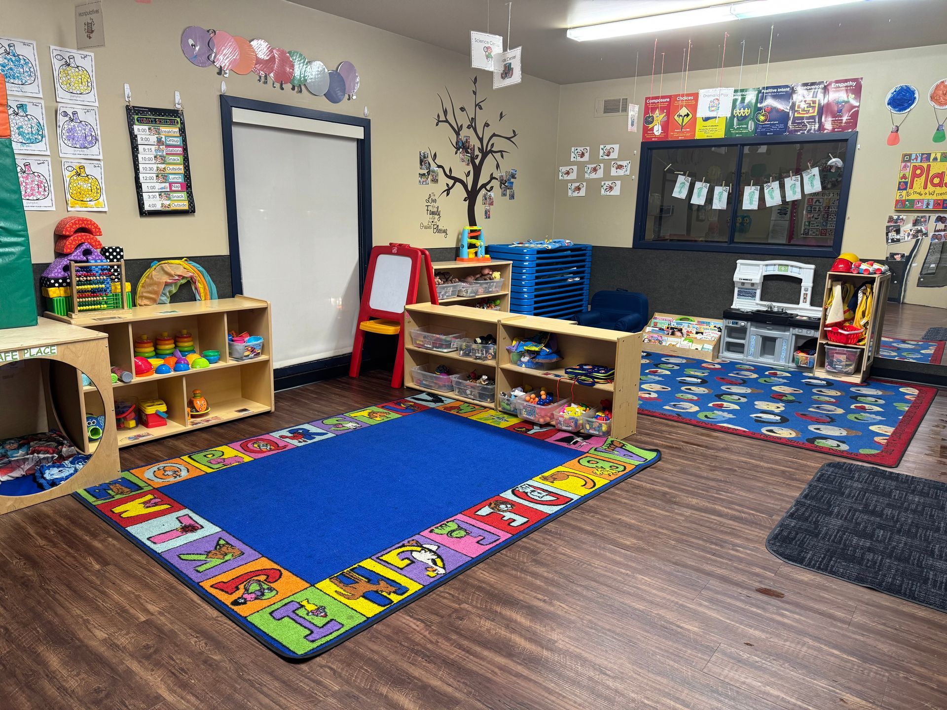 Playroom with wooden floor, toys, blue rug, and educational decorations.