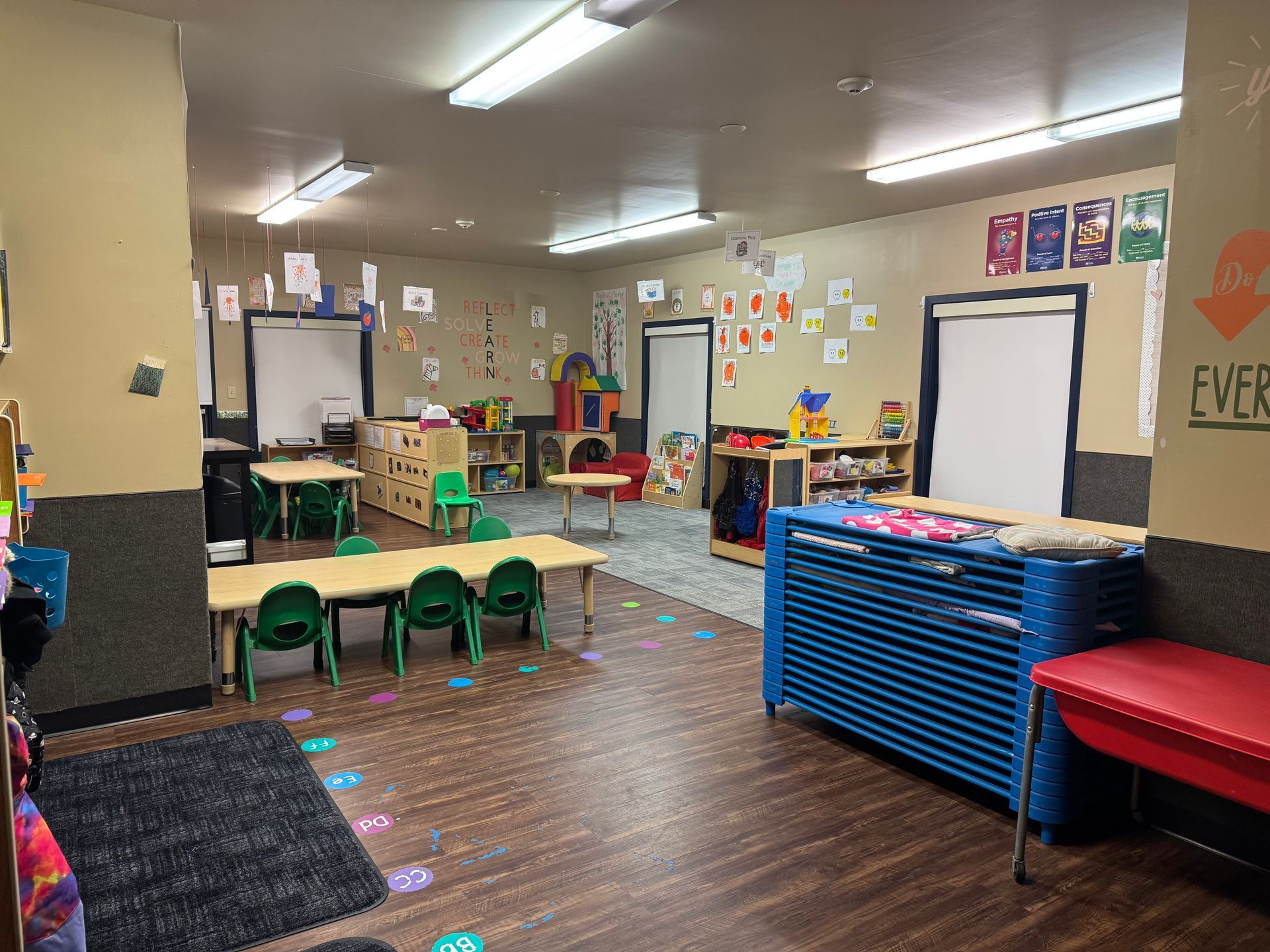 Childcare room with tables, chairs, and colorful decorations on the walls.