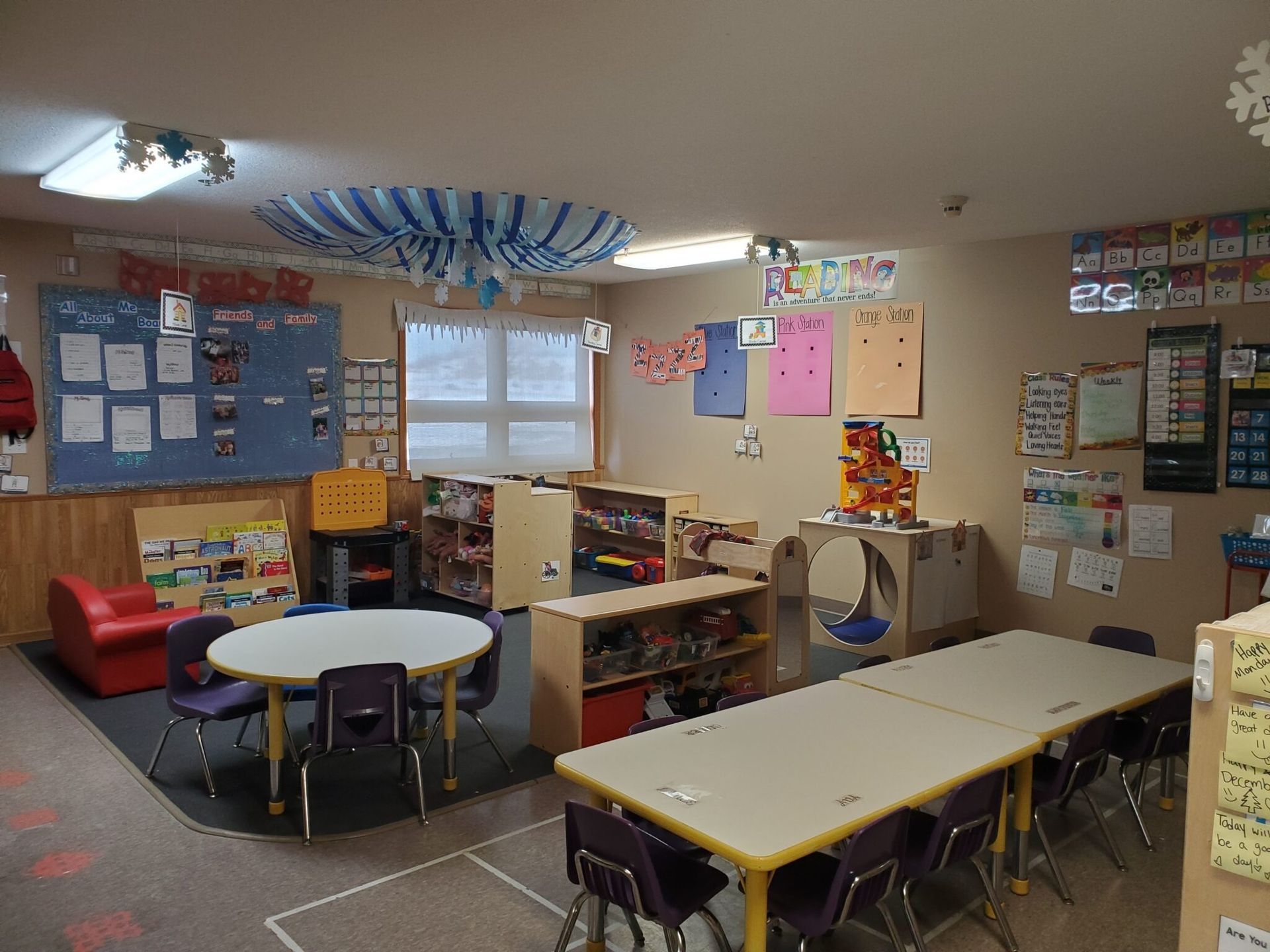 A classroom with tables, chairs, bookshelves, and decorations.