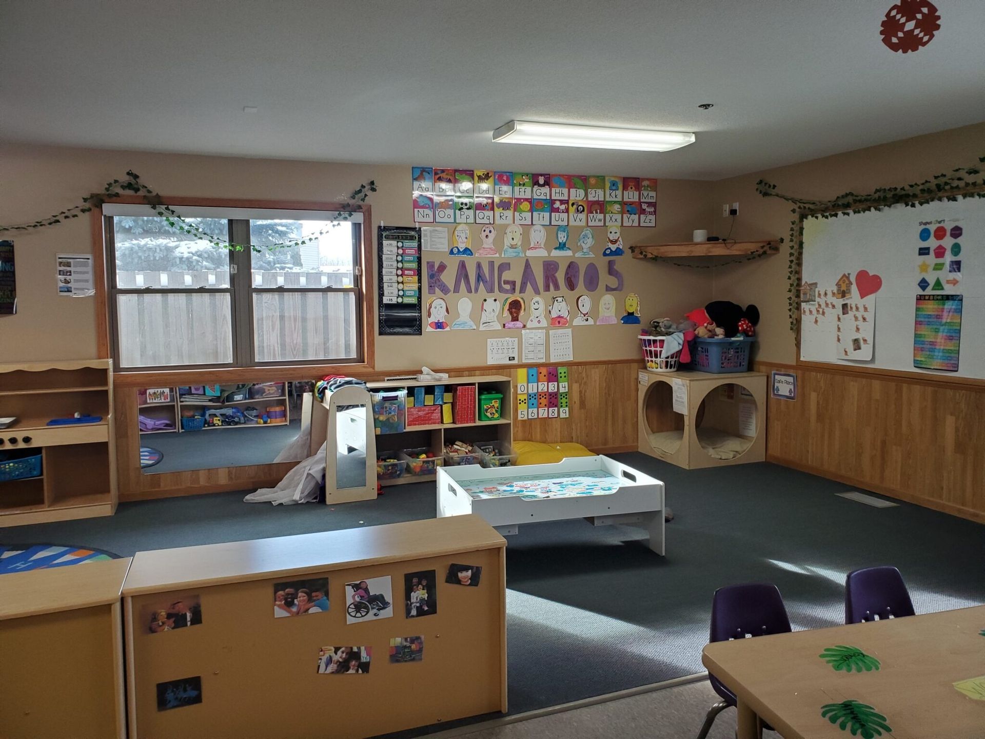 A children's classroom with wooden furniture, toys, and a window. 