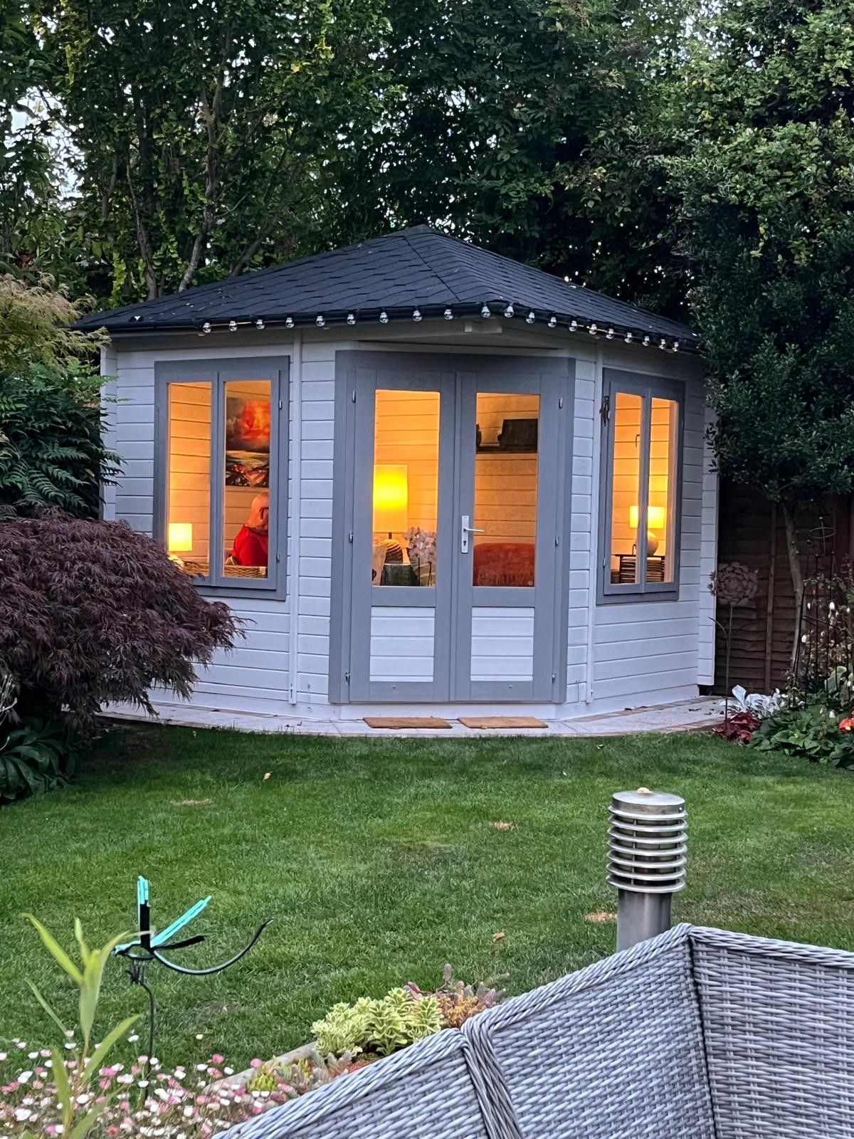 A wooden shed is sitting in the middle of a dirt yard.