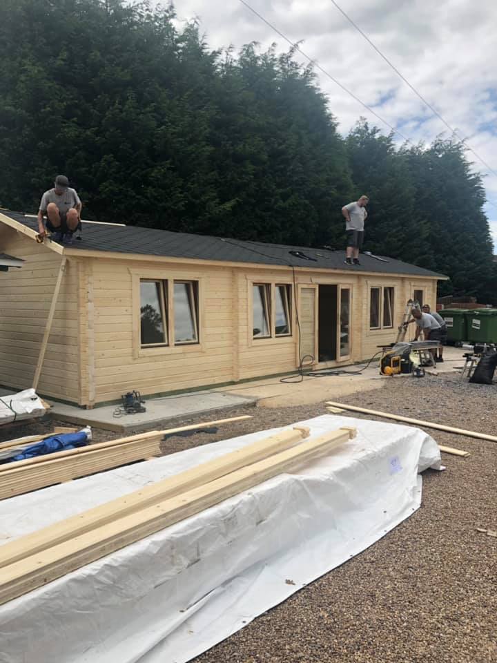 A group of people are working on the roof of a wooden house.