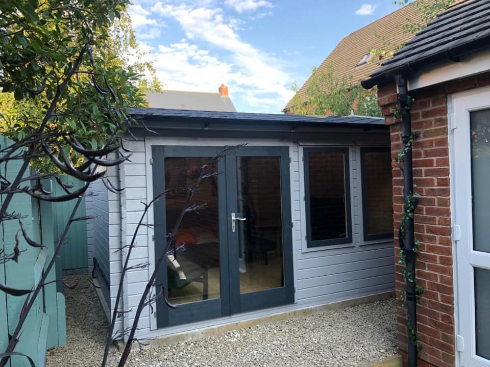 A small white house with a brick building in the background.