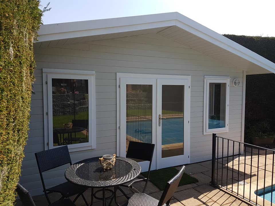 A white house with a table and chairs in front of it next to a pool.
