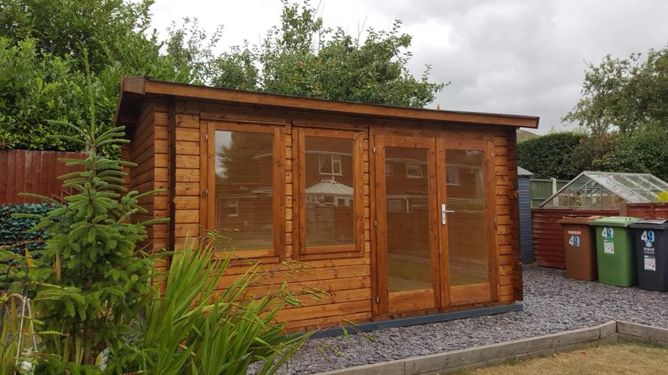 A wooden shed with a lot of windows and doors in a backyard.