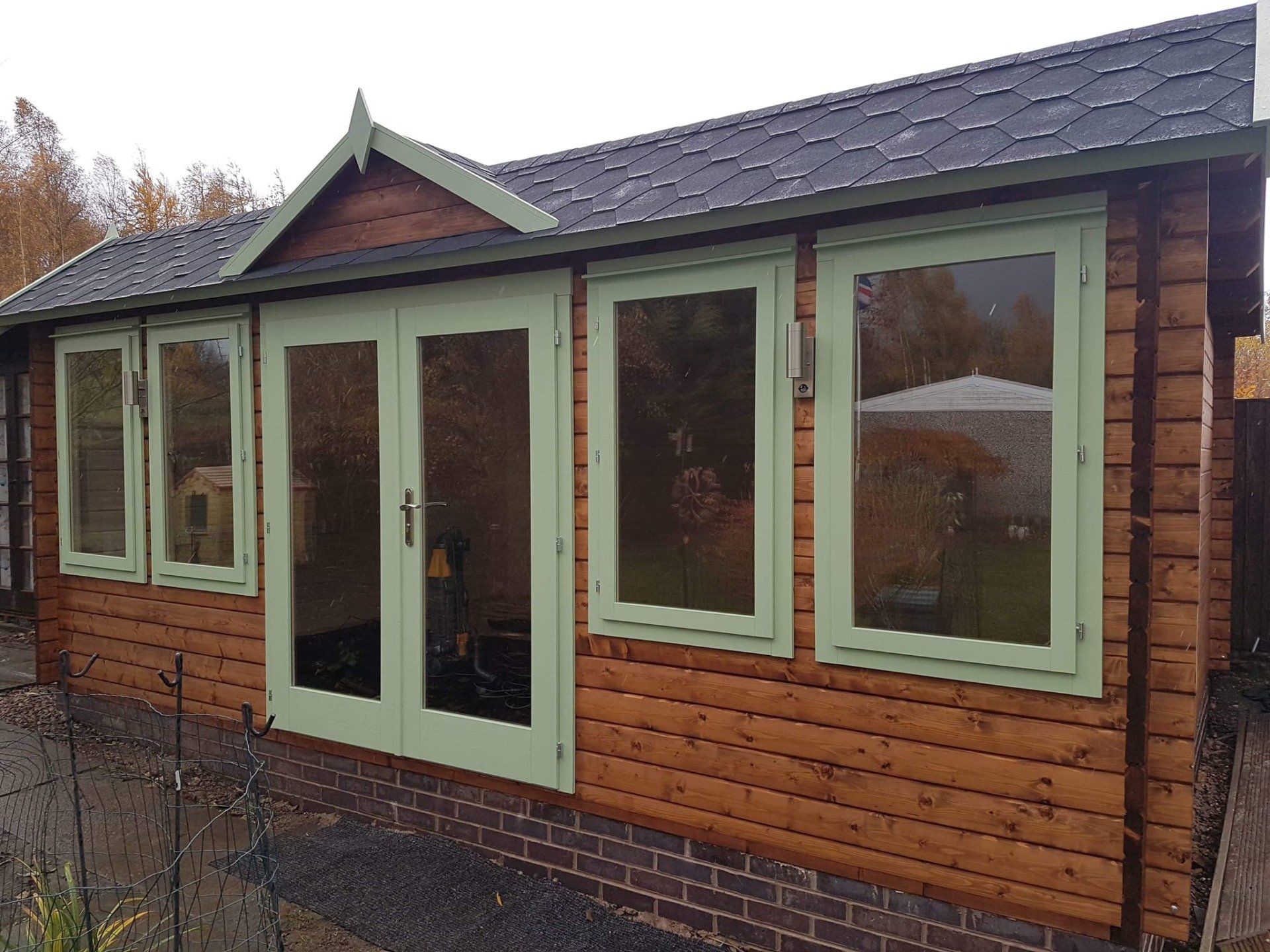 A wooden house with green windows and doors