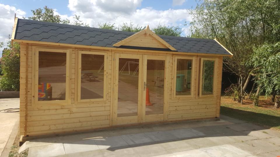 A large wooden house with a black roof is sitting on top of a concrete driveway.
