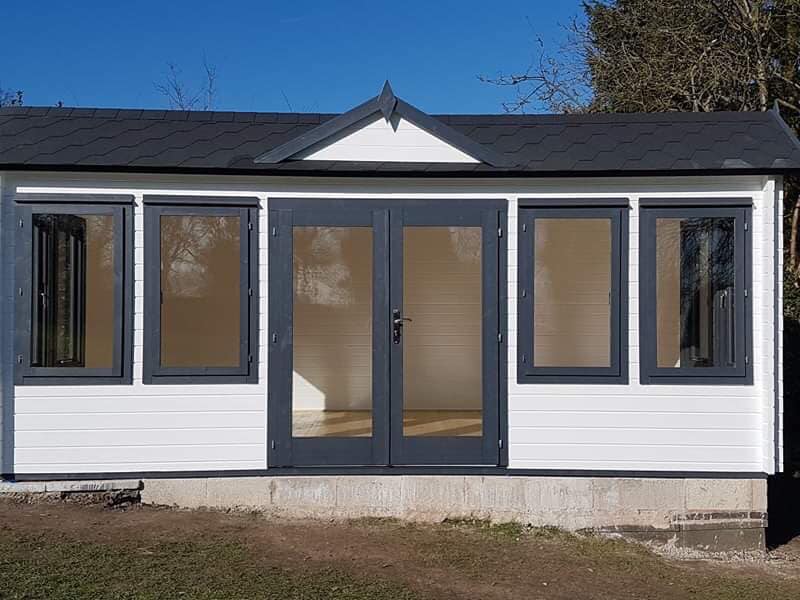A white house with a black roof and a lot of windows and doors.