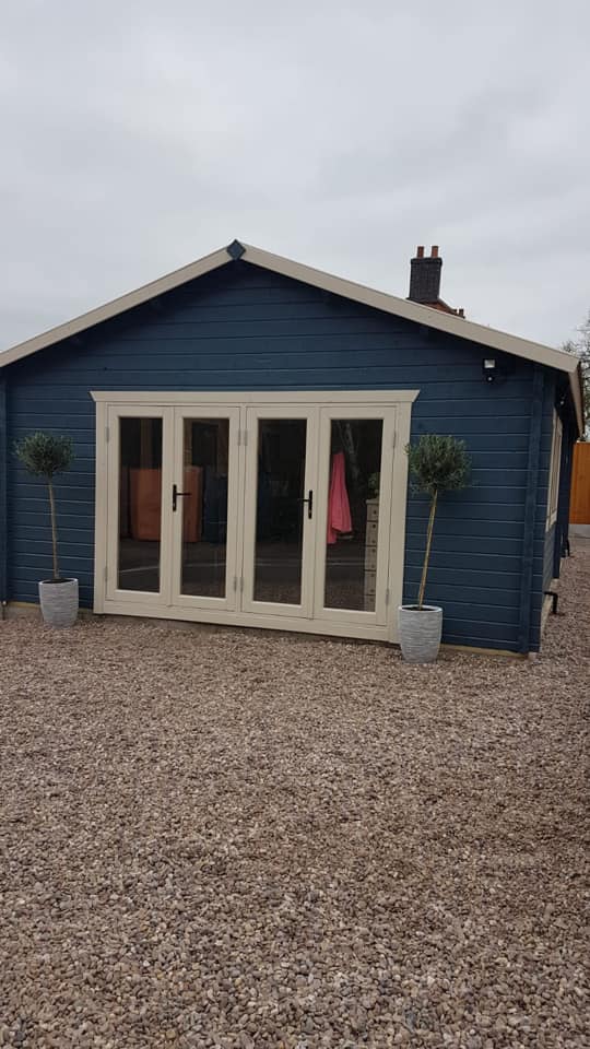 A blue house with white trim is sitting on top of a gravel driveway.
