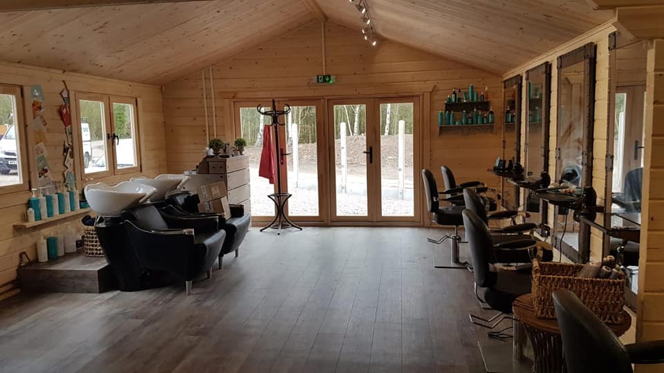 A large room with a lot of chairs and mirrors in a hair salon.