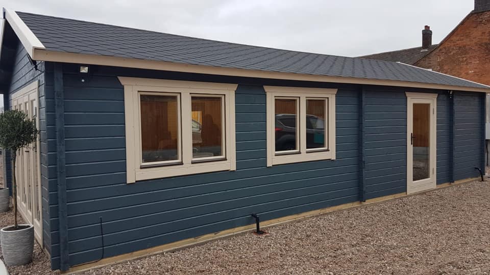 A blue house with white trim and windows is sitting on top of a gravel driveway.