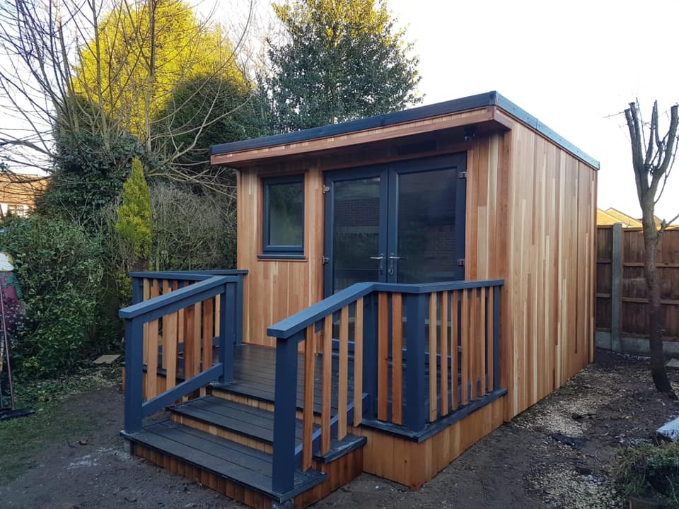 A wooden shed with stairs leading up to it in a garden.