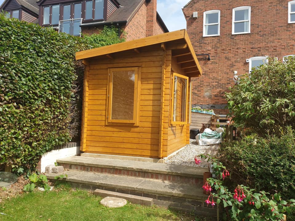 A small wooden shed is in the backyard of a house.