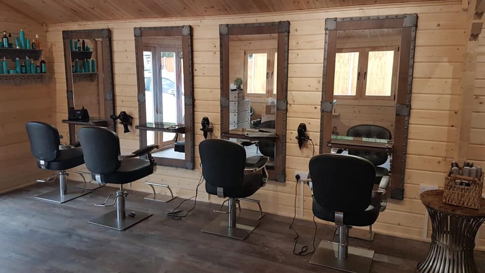 A hair salon with three chairs and three mirrors.