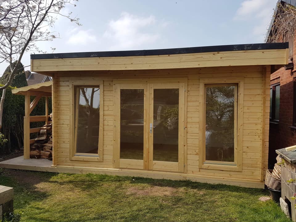 A small wooden house with lots of windows and doors in a backyard.