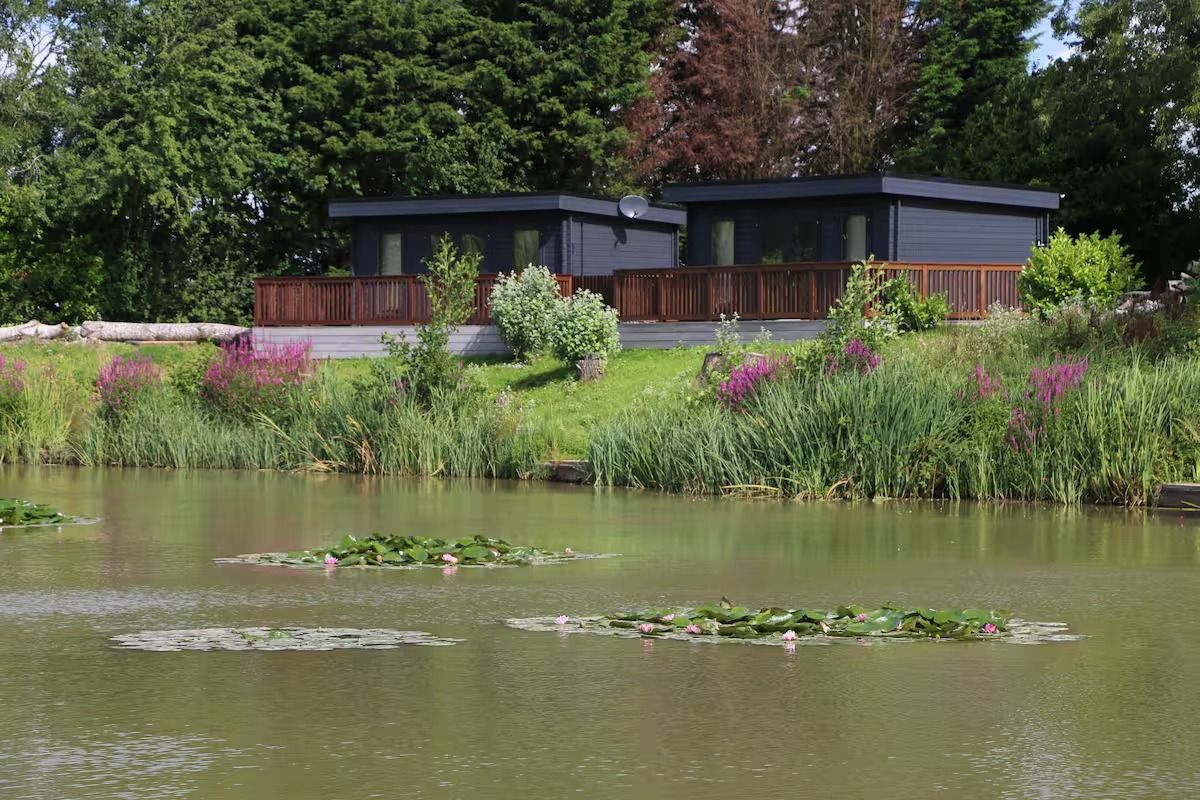A couple of Log Cabin are sitting on the shore of a lake.