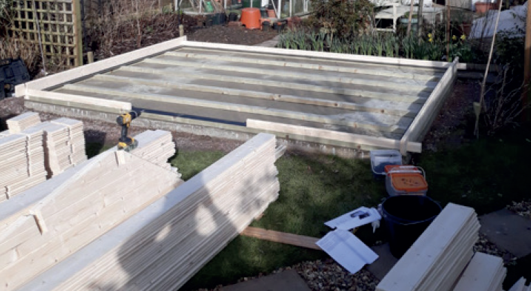 A wooden structure is being built in a garden.