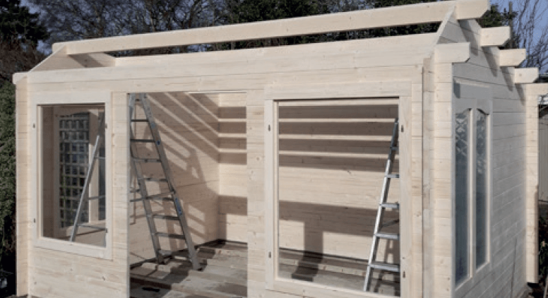 A wooden house is being built with a ladder.
